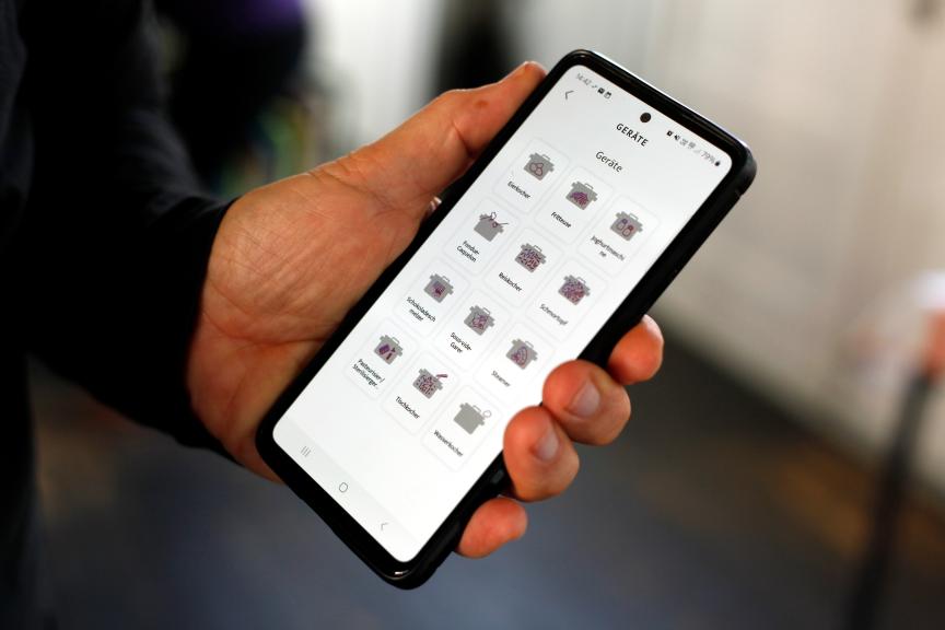telefon in hand mit app und geräten